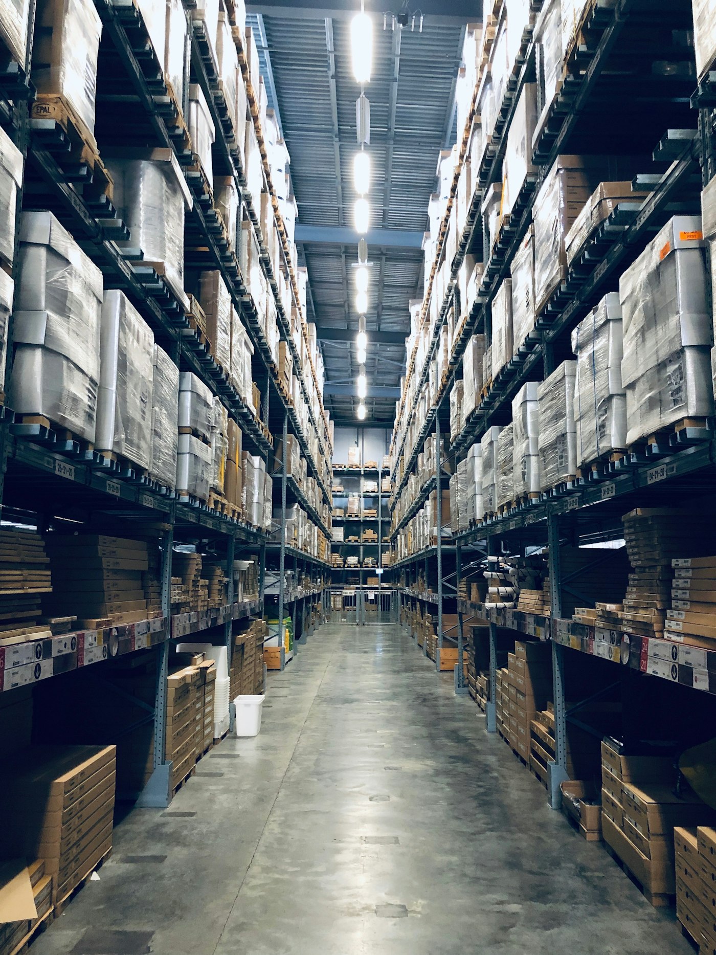 Warehouse aisle with stocked racks under bright lights
